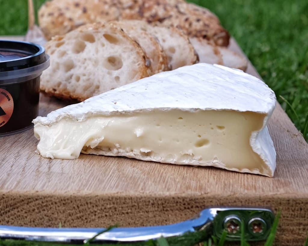 Slice of Brie de Nangis oozy on a picnic platter