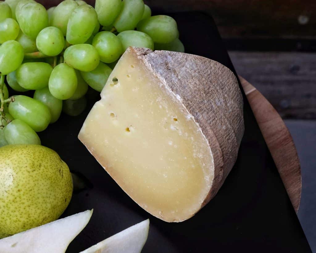 Wedge of Wyfe of Bath hard cheese with green grapes