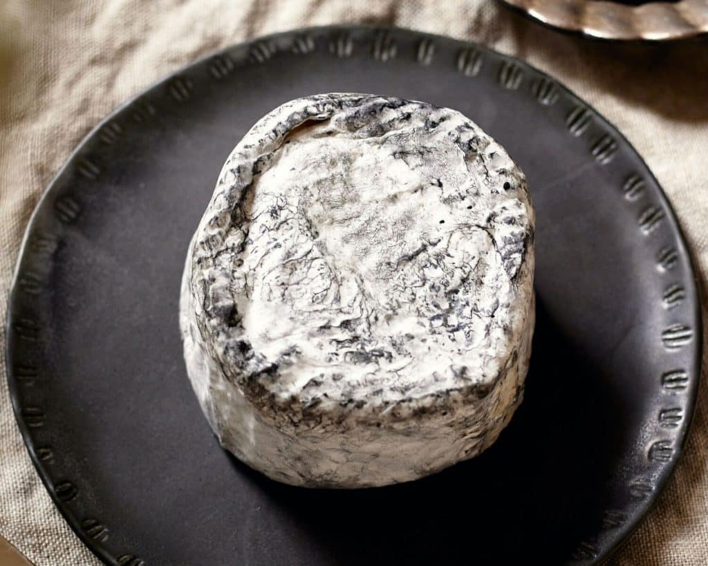 Soft Black Pearl cheese on a black plate