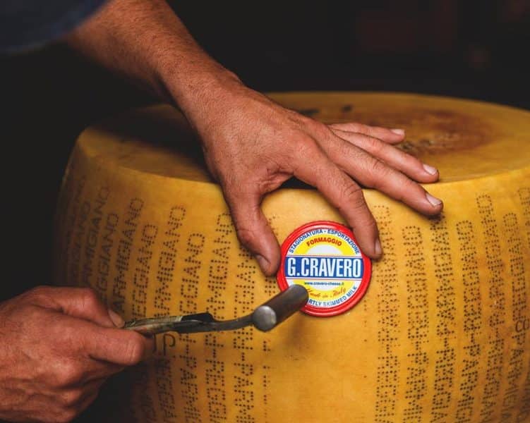 Affineur hammering a G.Cravero stamp onto wheel of hard cheese