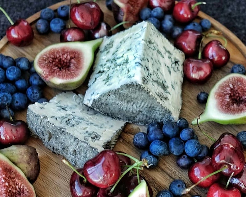 Wedges of Persillé de Rambouillet blue cheese with berries and cherries