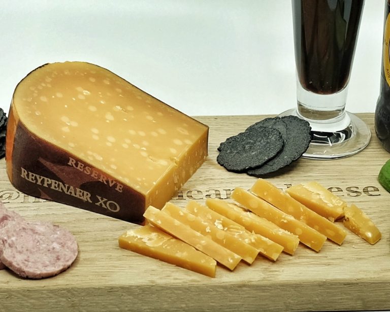 Wedge of Reypenaer XO with slices cut off and served with dark beer