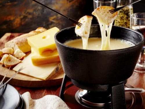 Dipping bread into classic Swiss Cheese Fondue pot