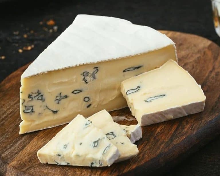 Soft creamy blue cheese Cambozola on a wooden board