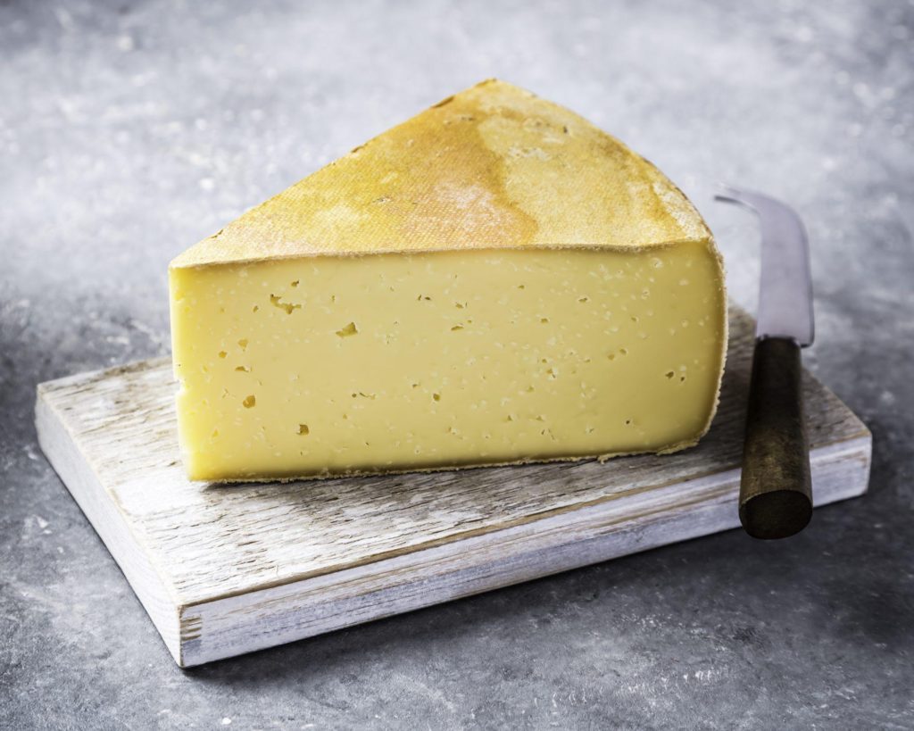 Wedge of semi-hard cheese Ogleshield on cheese board