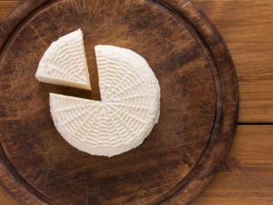 Fresh white Kalathaki Limnou Greek cheese on wooden board