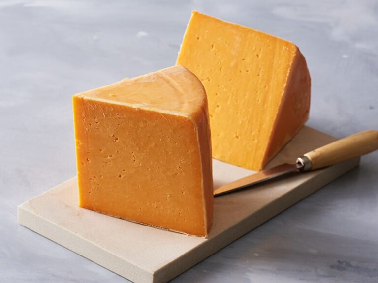Wedge of orange Colby cheese on a wooden board