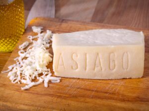 Wedge of Asiago Italian hard cheese being grated