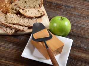 Block of Gjetost Norwegian brown cheese being sliced for a sandwich