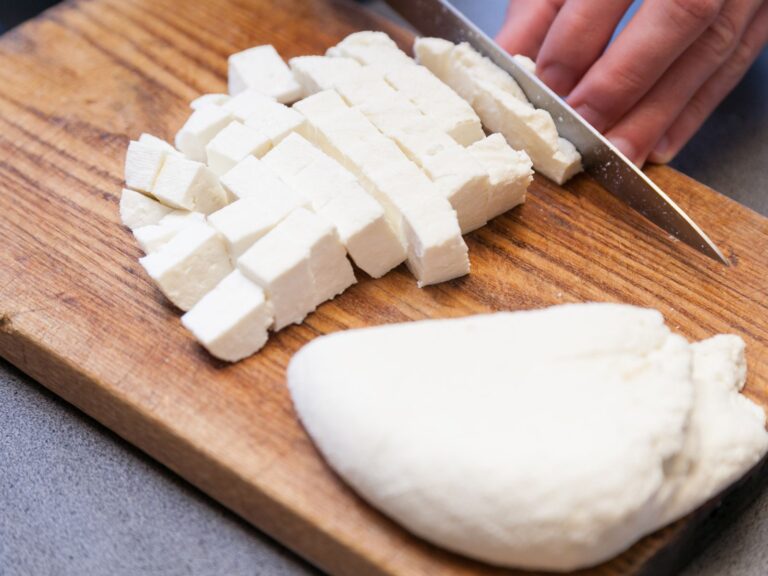 Cook dicing Paneer cheese on a wooden chopping board