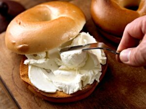 Spreading Philadelphia Cream Cheese on a bagel using a spreader knife