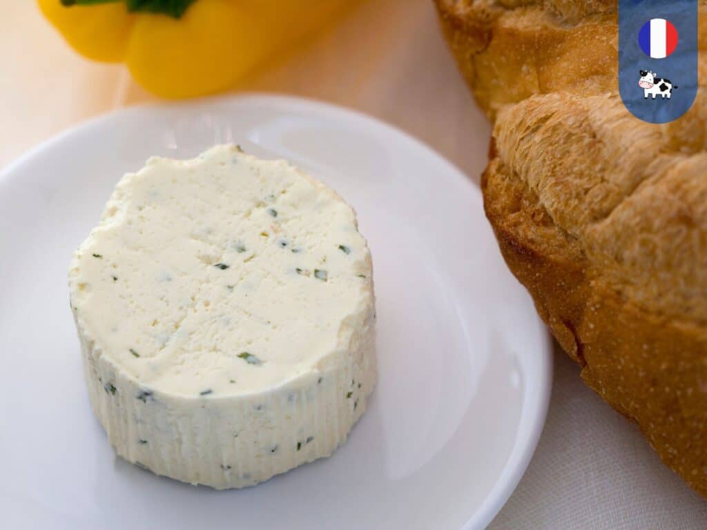 Round of Boursin Cheese on a white plate next to French baguette